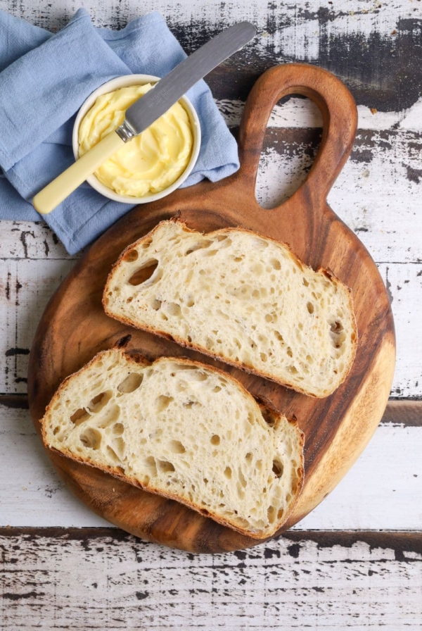 A photo of 2 slices of sourdough bread laid out on a round wooden board.