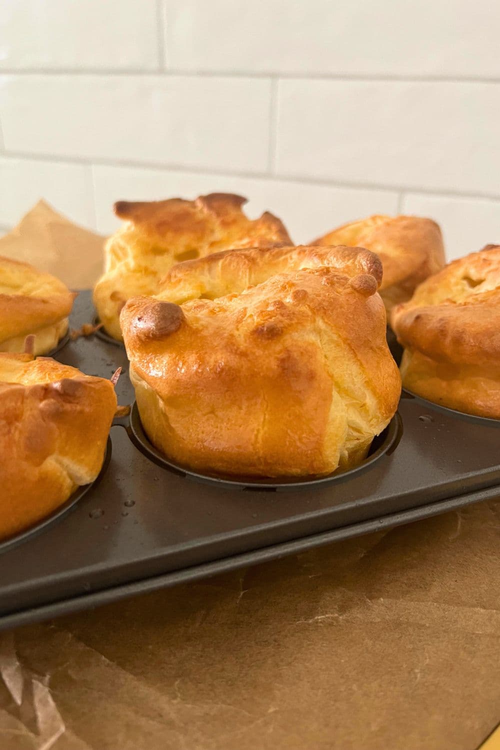 A tray of sourdough discard popovers that have just come out of the oven, they are super puffy and golden brown.