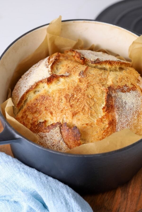 A loaf of sourdough bread sitting inside a black Dutch oven.