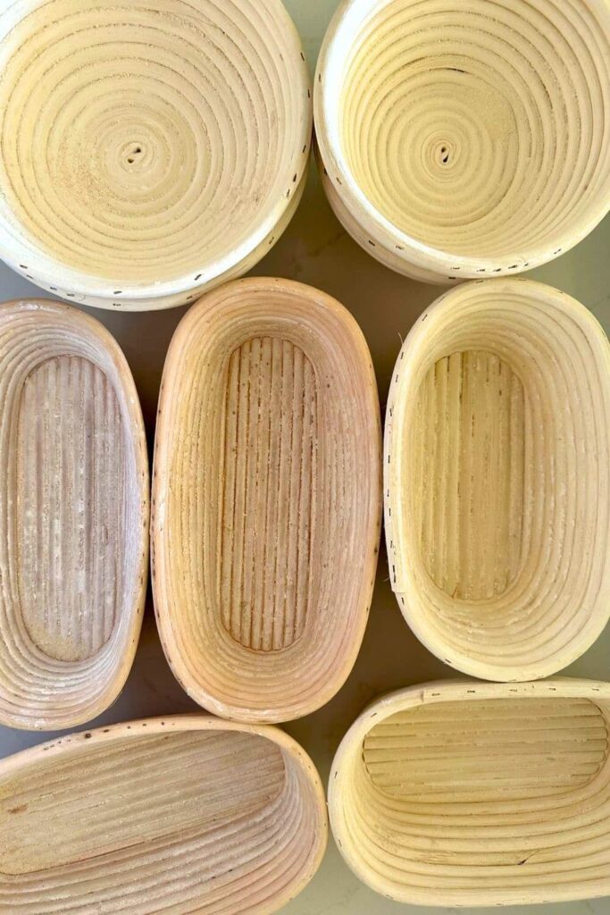 Sourdough glossary - a photo showing 7 banneton baskets arranged on a counter top. They have all been used and show some flour stuck to the inside of the rattan.