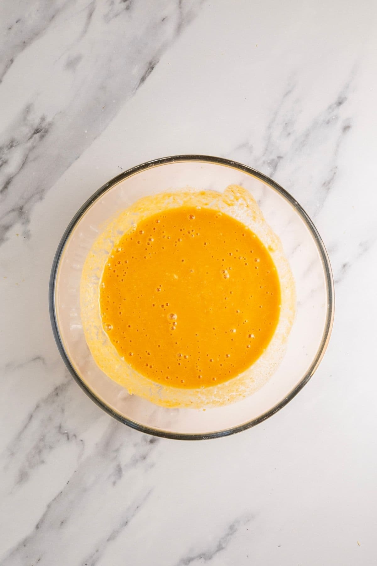 A glass bowl filled with the liquid ingredients needed to make an artisan pumpkin loaf.
