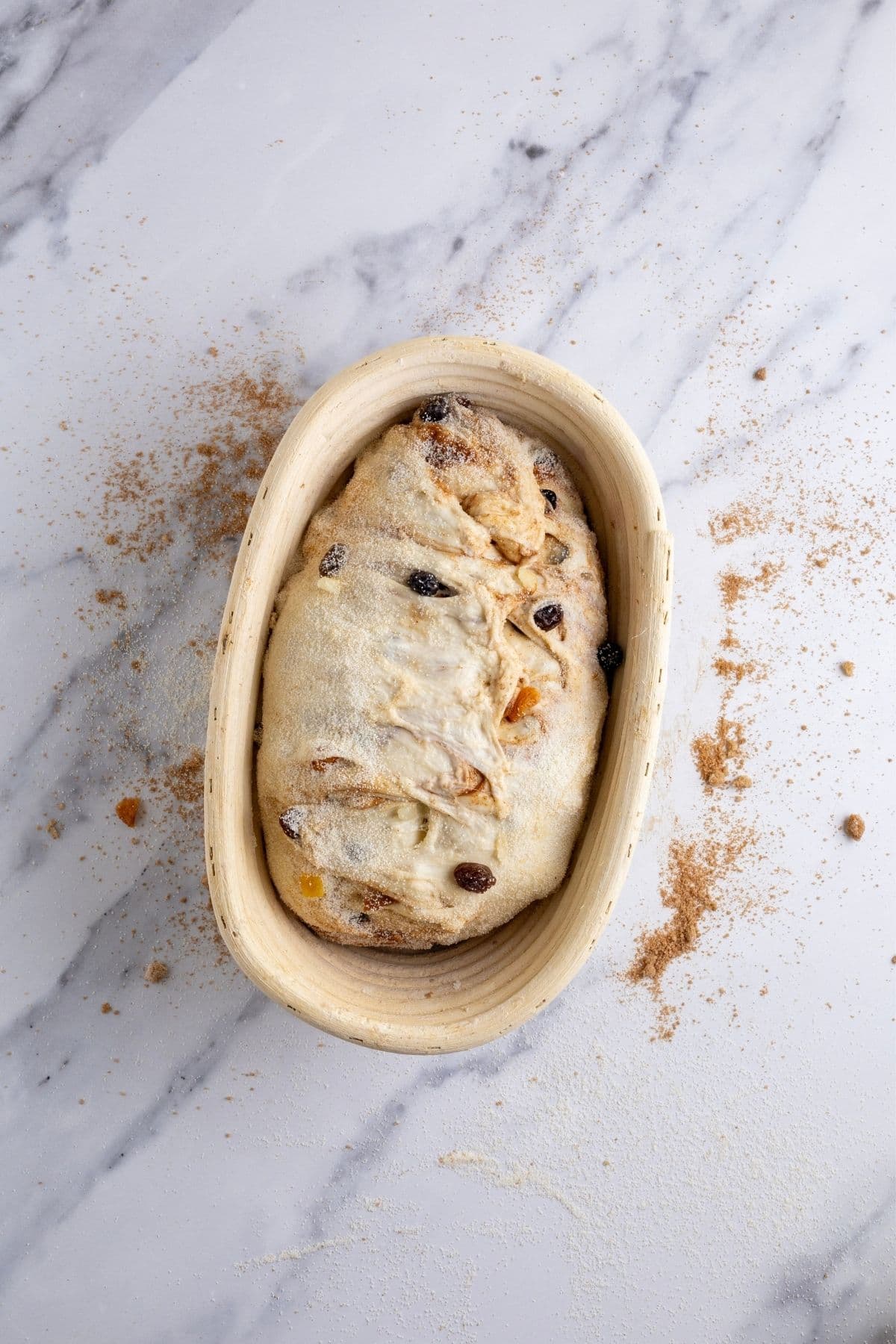 Sourdough fruit loaf inside a 9" banneton. The top of the dough has been stitched together to keep all of the cinnamon sugar filling inside.