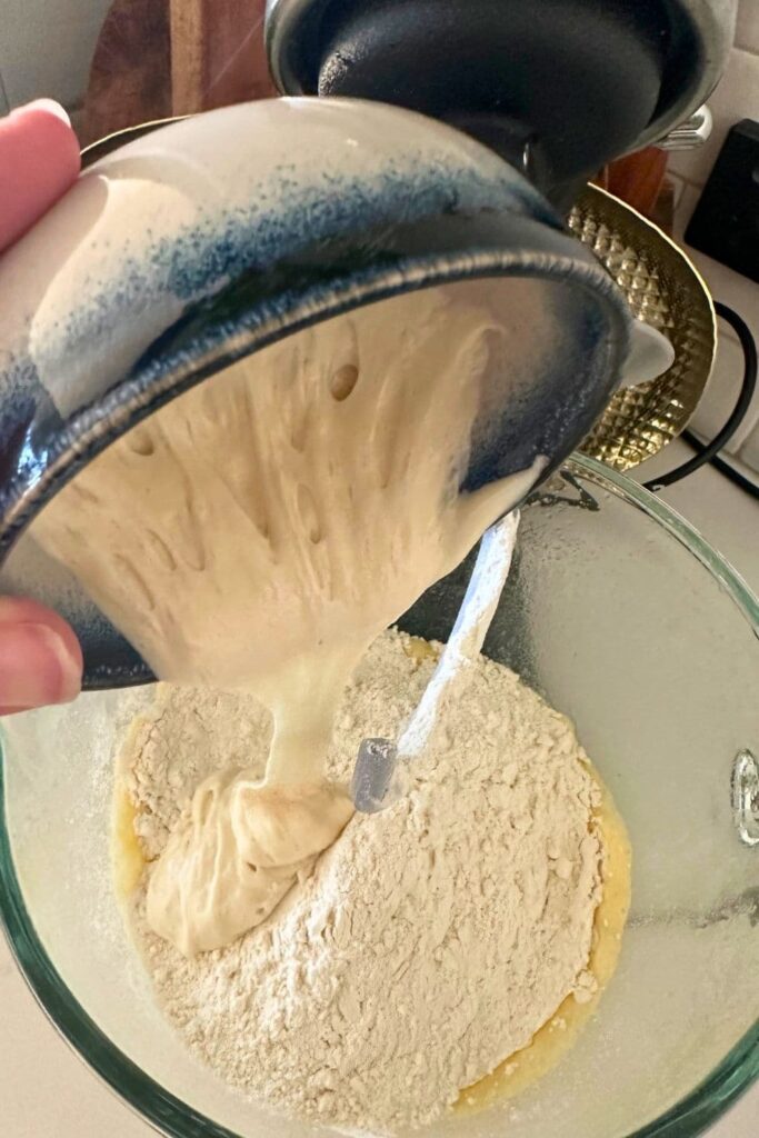 Sourdough starter being added to the other ingredients in the bowl of the stand mixer.