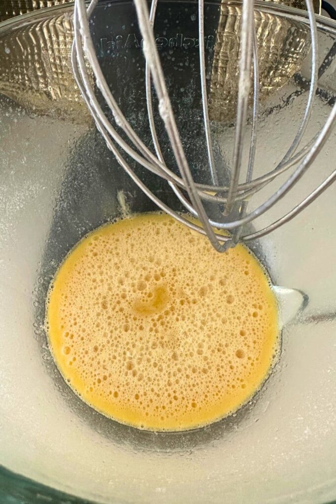 The liquid ingredients needed to make sourdough Hawaiian rolls being whisked together in the bowl of a stand mixer.