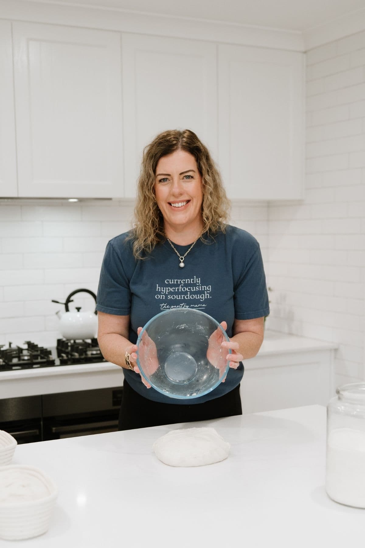 A photo of Kate Freebairn from The Pantry Mama holding a relatively clean bowl that she has just tipped sourdough out of onto the counter.