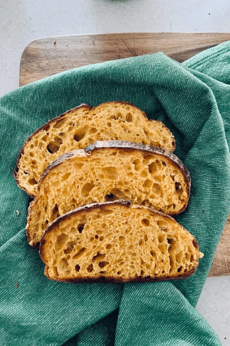 3 slices of sourdough pumpkin bread sitting on a green dish cloth.