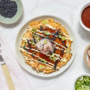 A Sourdough Okonomiyaki pancake displayed on small white plate.