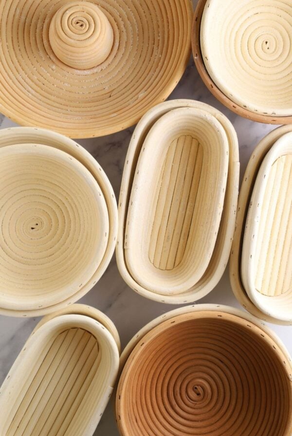 A flat lay of different banneton baskets. There are large and small round bannetons, long oval bannetons, short oval bannetons and a banneton for a corrone.