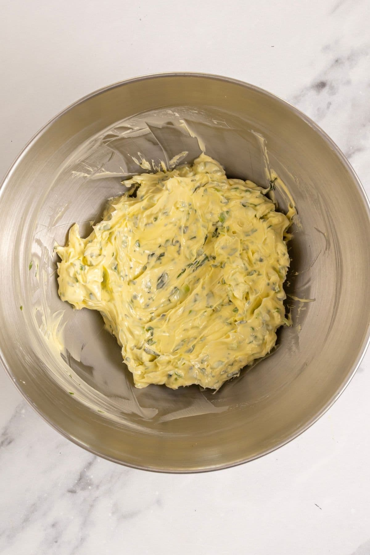 A stainless steel bowl filled with the finished whipped herb butter.