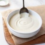 Sourdough Bechamel Sauce served in a white bowl with a vintage spoon.