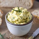 a small pottery dish filled with whipped herb butter and topped with fresh rosemary.