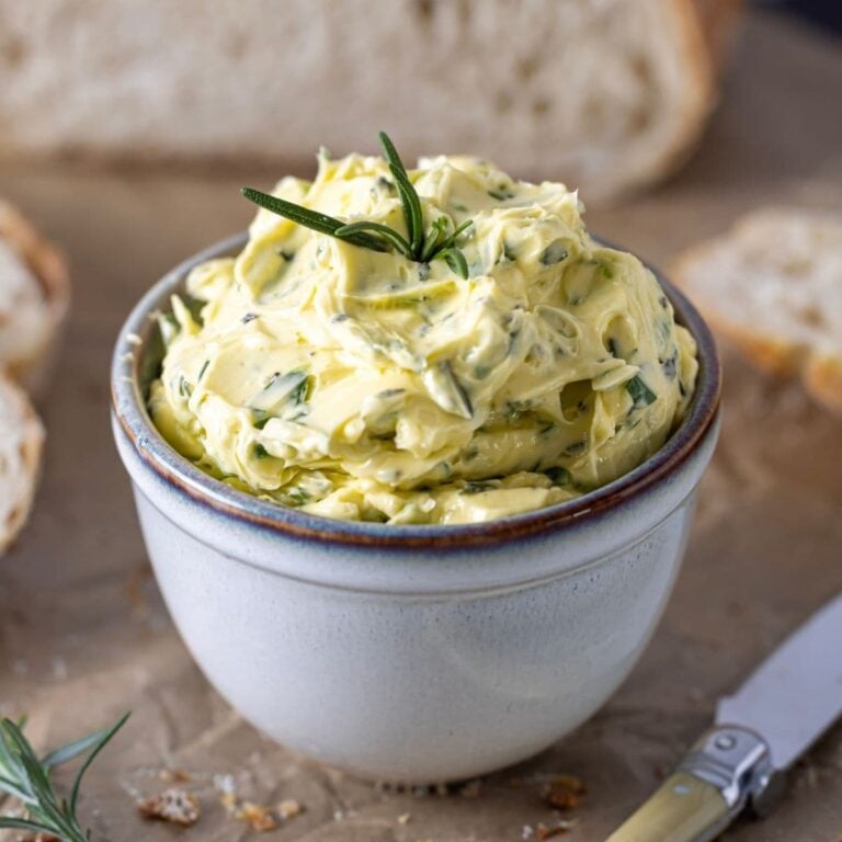 a small pottery dish filled with whipped herb butter and topped with fresh rosemary.