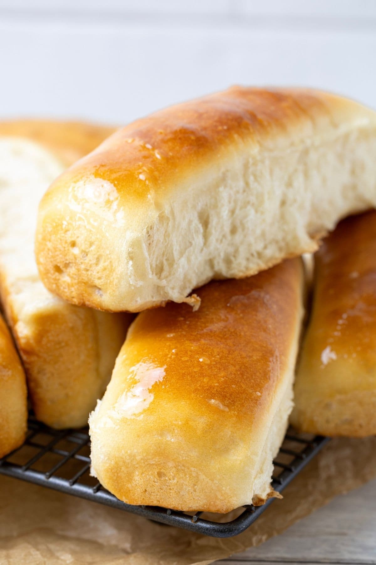 Close up photo of freshly baked sourdough hot dog buns cooling on a wire rack.