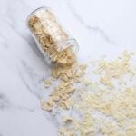 A jar of dried sourdough starter that has been tipped out onto the kitchen counter spilling all the dried sourdough starter flakes.