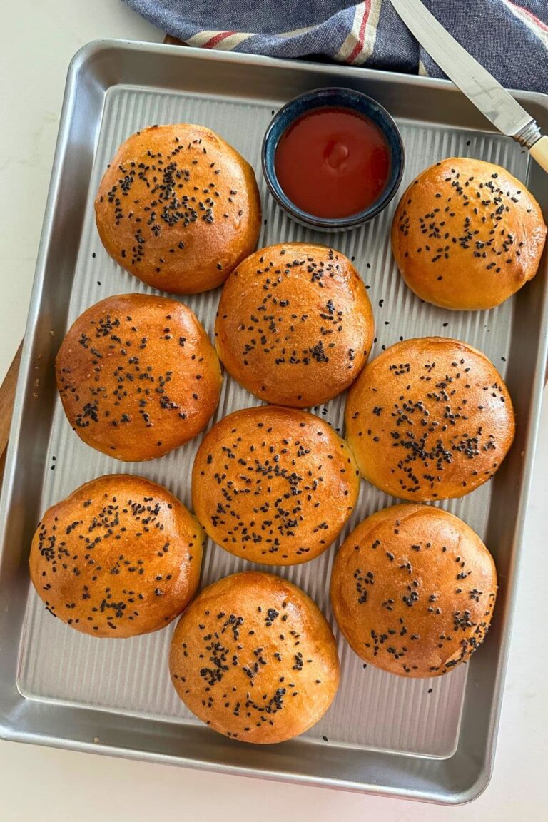 A tray of sourdough discard hamburger rolls decorated with black sesame seeds ready for 4th of July celebrations.