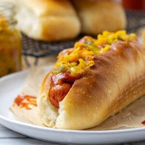 A close up photo of a sourdough hot dog bun filled with a frankfurt and mustard relish.