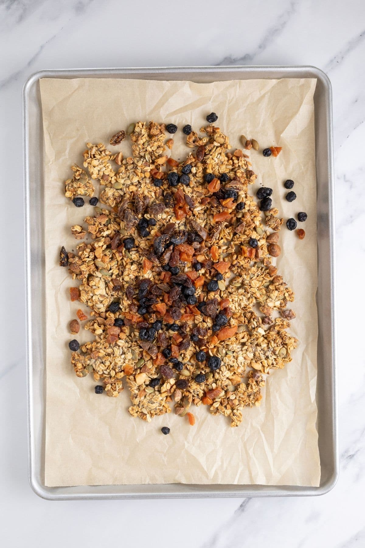 Adding dried fruit on top of cooled granola.