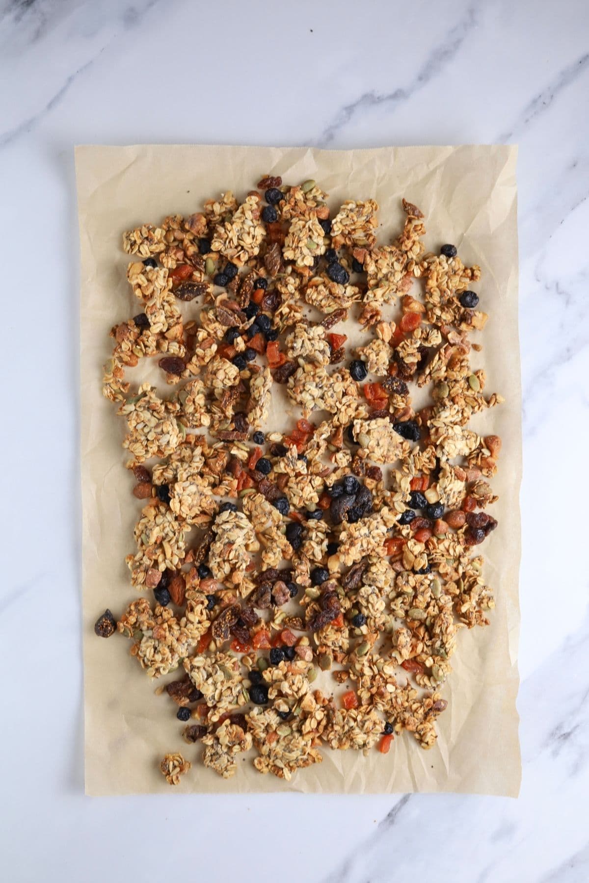 Finished sourdough granola broken into clusters and laid out on a piece of parchment paper.