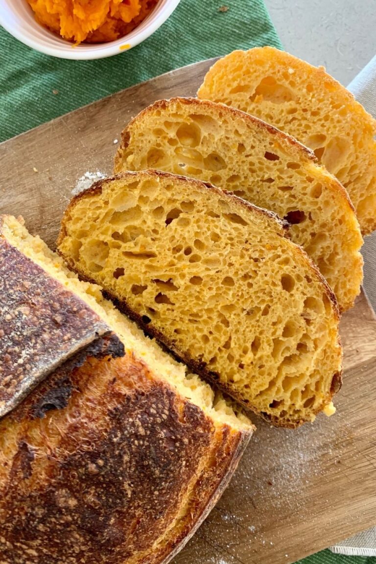 A loaf of sourdough pumpkin bread that has been sliced and layed open to see the crumb inside.