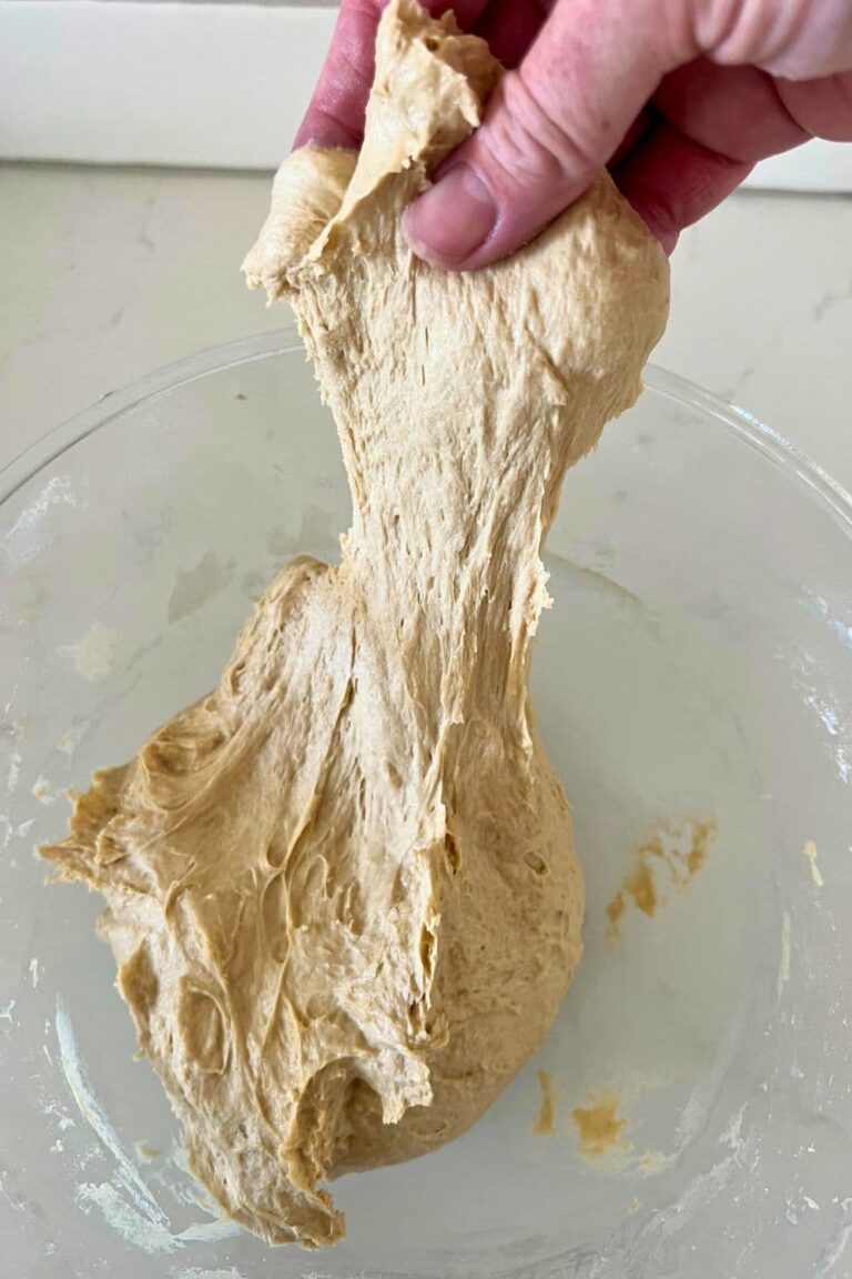 A bowl of wet, sticky sourdough being stretched up out of the bowl.