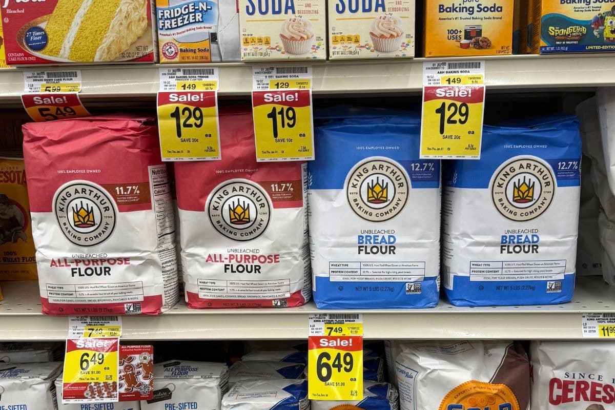 A close up of a shelf in the grocery store showing bags of King Arthur all-purpose and bread flour sitting side by side.
