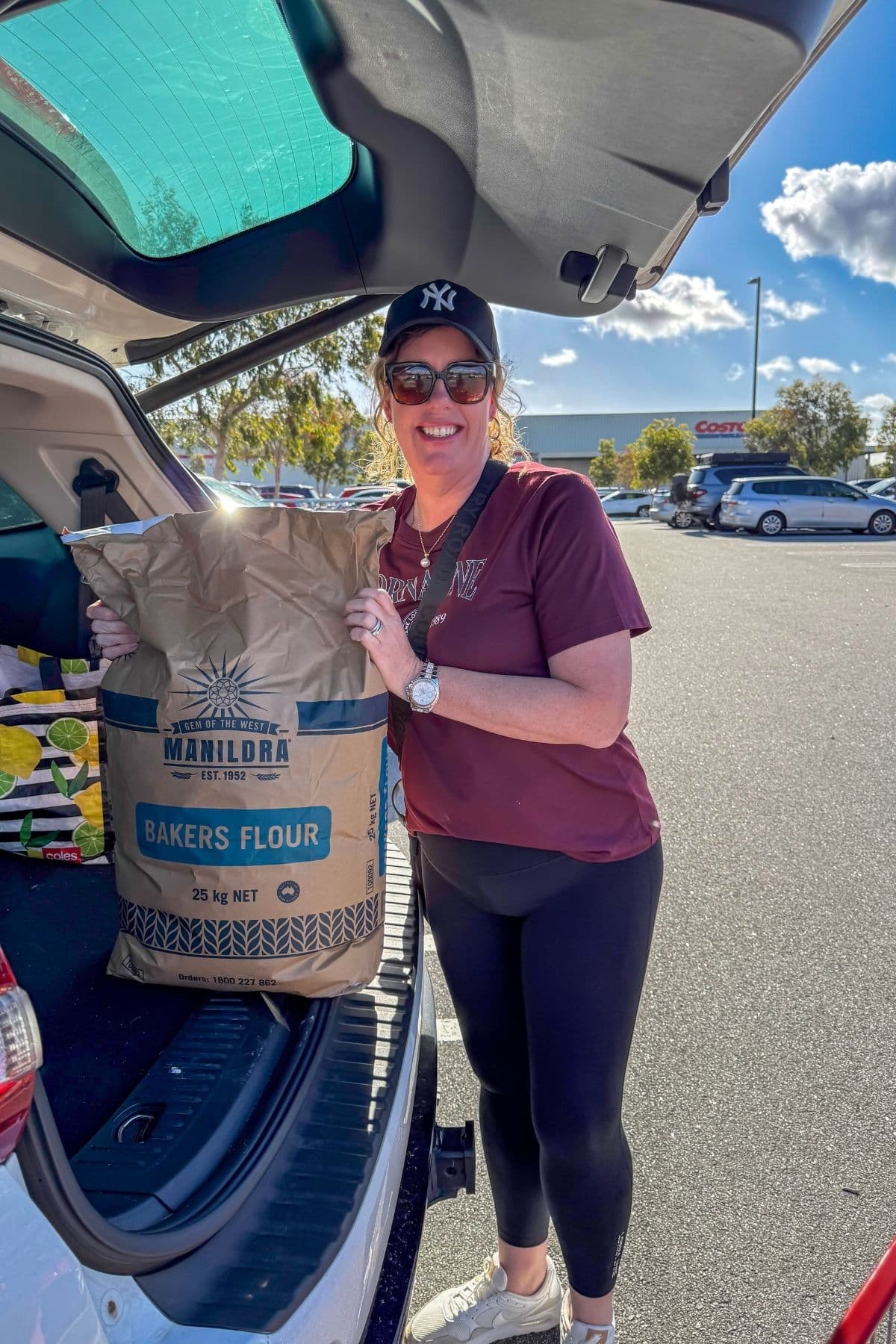 Kate from The Pantry Mama standing at the back of her car outside Costco holding a bag of Manildra Baker's Flour.
