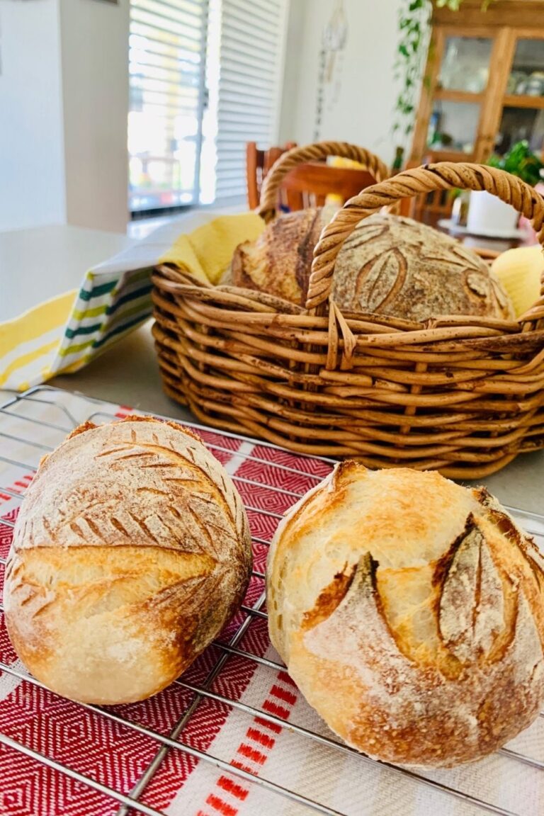 Mini sourdough boules or crusty sourdough rolls sitting on a teatowel and in a basket