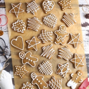 A flat lay of lots of different sourdough gingerbread cookies that have been decorated with white royal icing.