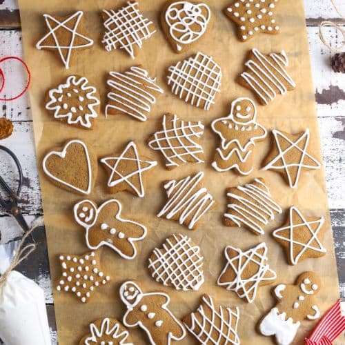 A flat lay of lots of different sourdough gingerbread cookies that have been decorated with white royal icing.