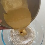 Pouring the wet ingredients into the bowl of dry ingredients.