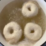 Boiling sourdough bagels in honey water to set the crust.