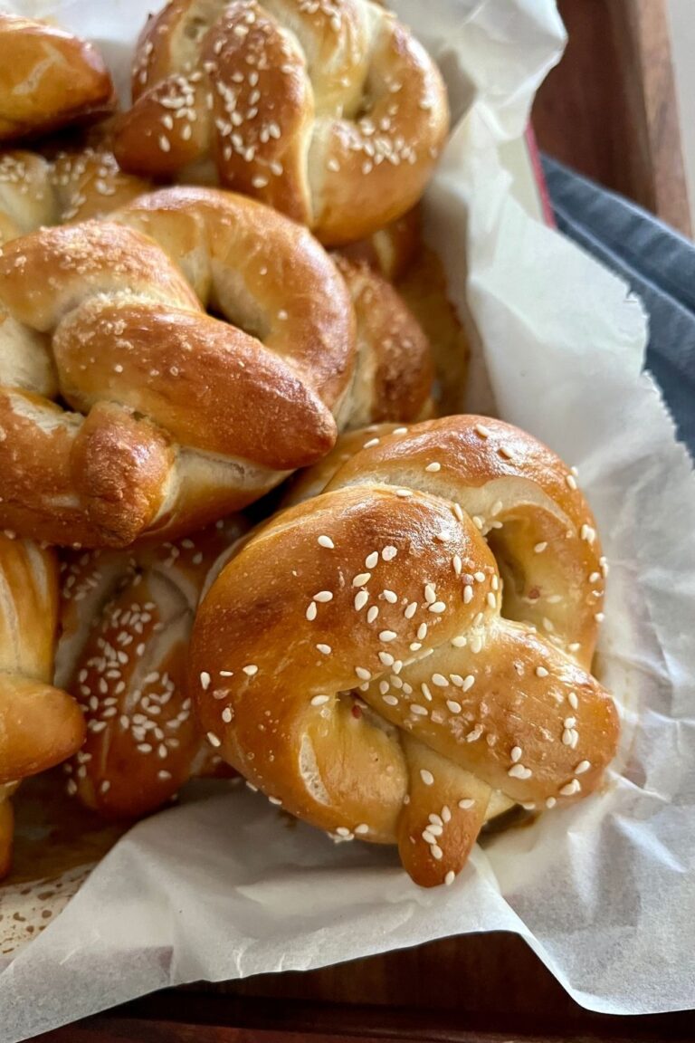 Soft Sourdough Pretzel Recipe - pretzels sitting in a wooden tray on top of a blue dish cloth