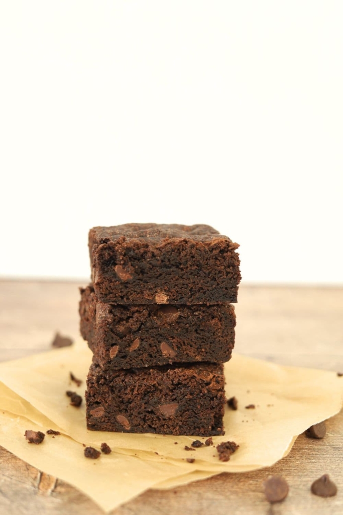 A stack of 3 sourdough brownies arranged so you can see the crackly top and the fudgy middle.