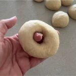 Shaping sourdough egg bagels by poking a hole in each ball of dough.