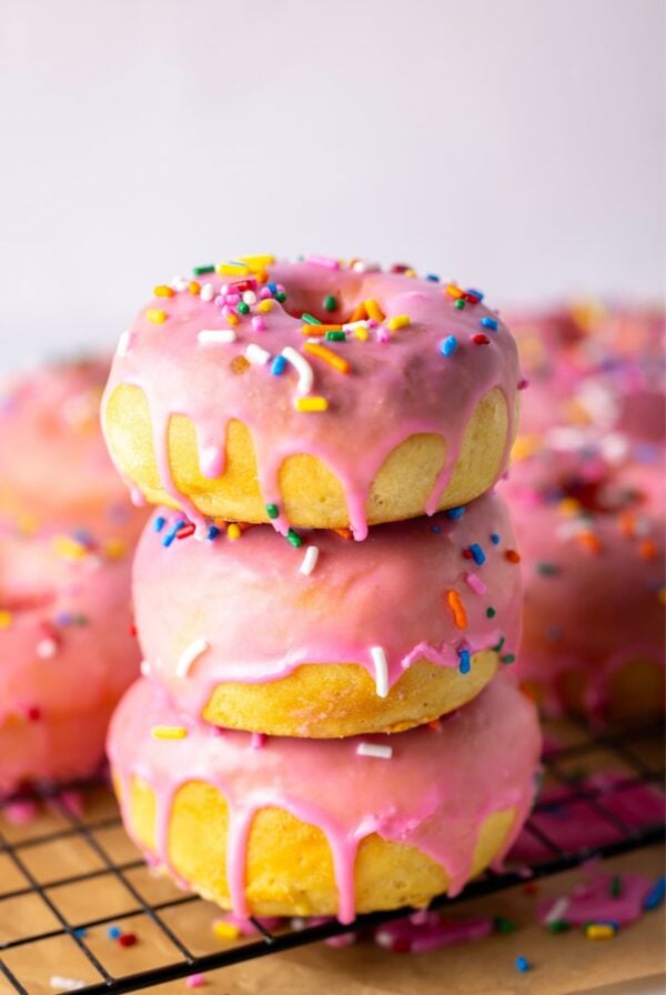 A stack of 3 sourdough baked donuts drizzled in pink glaze.