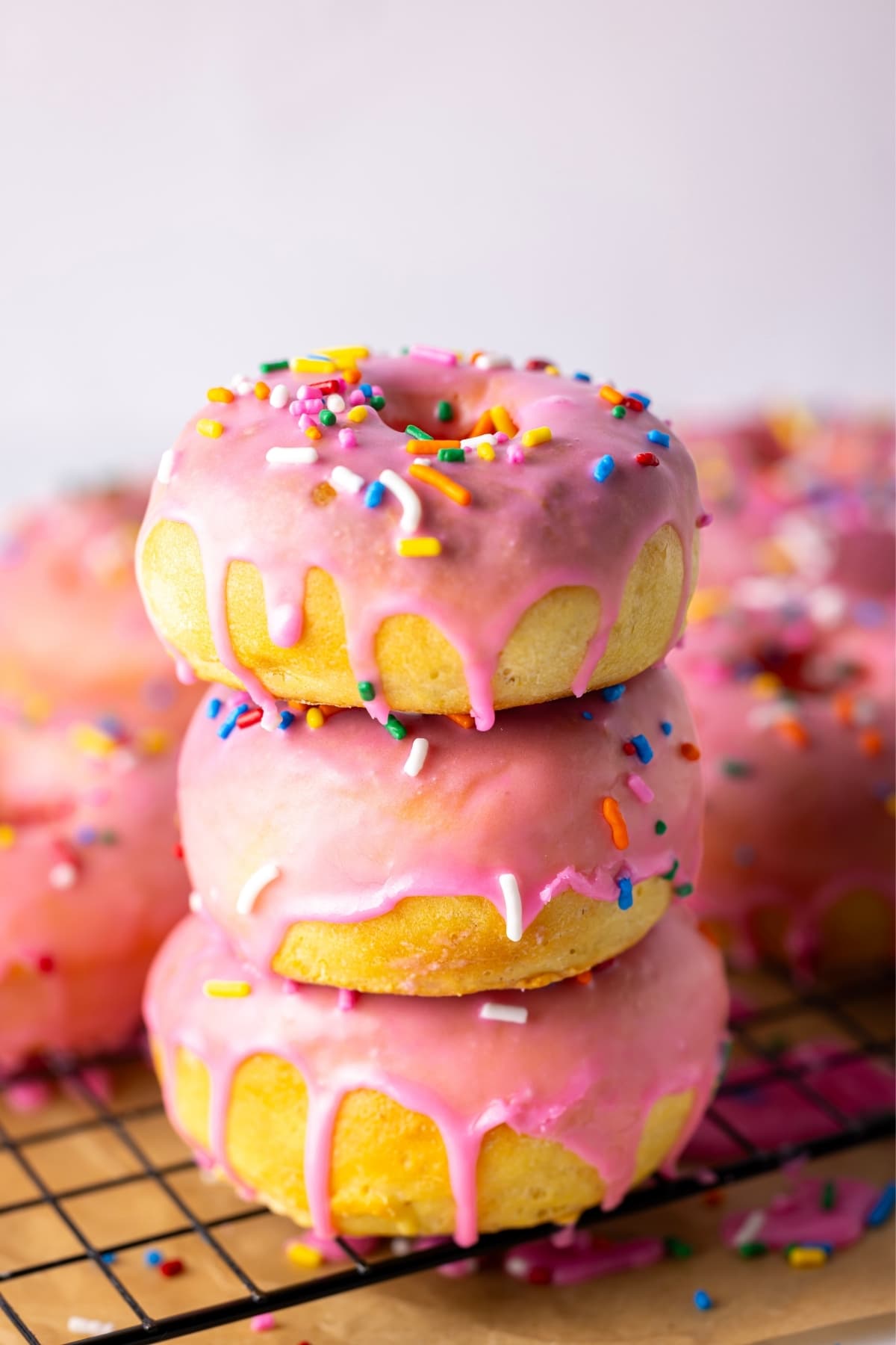 A stack of 3 sourdough baked donuts drizzled in pink glaze.