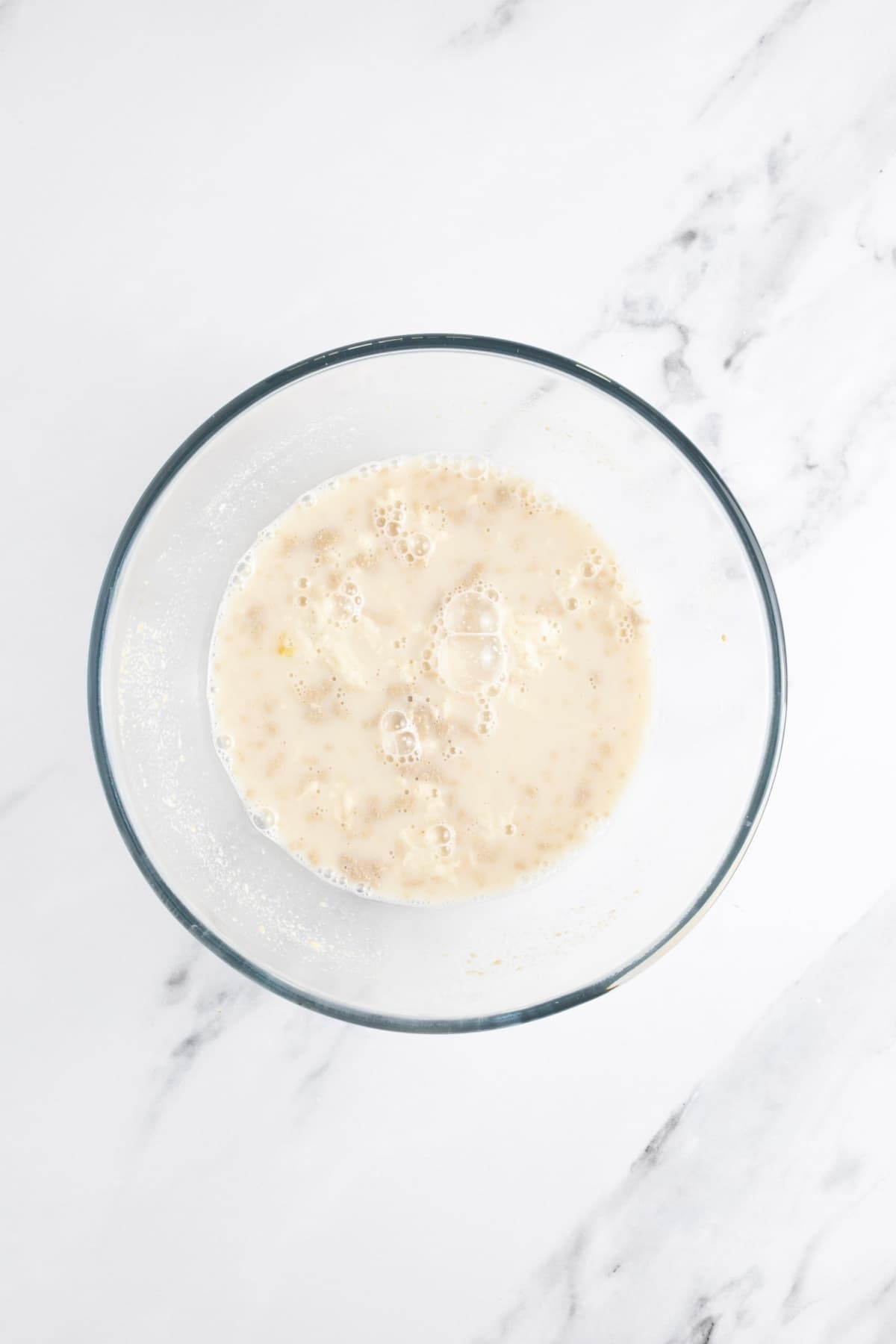 A glass bowl filled with water, honey and sourdough starter.