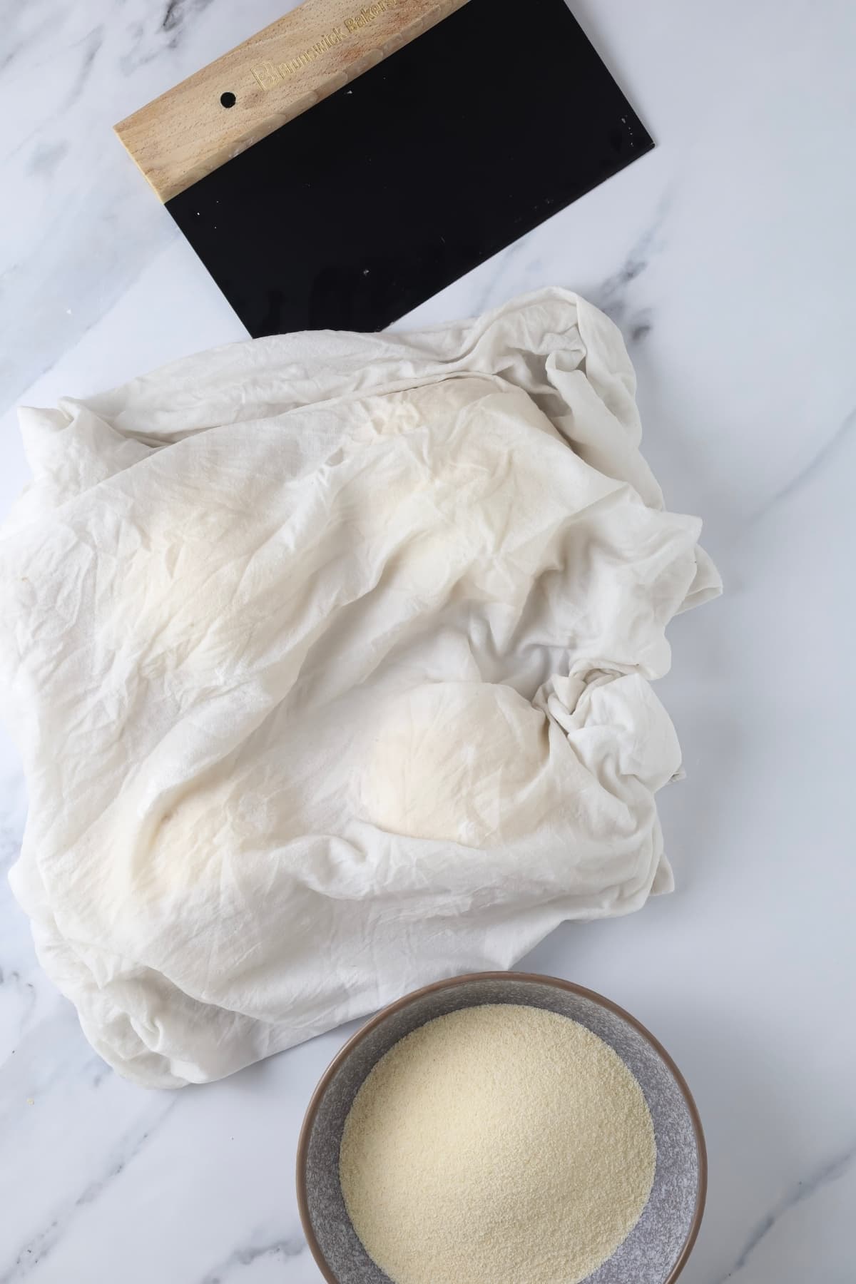 Sourdough discard pizza dough balls covered with a damp flour sack tea towel.