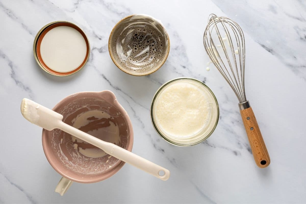 A horizontal image showing the cream and yogurt being added together in a jar and stirred until well combined.
