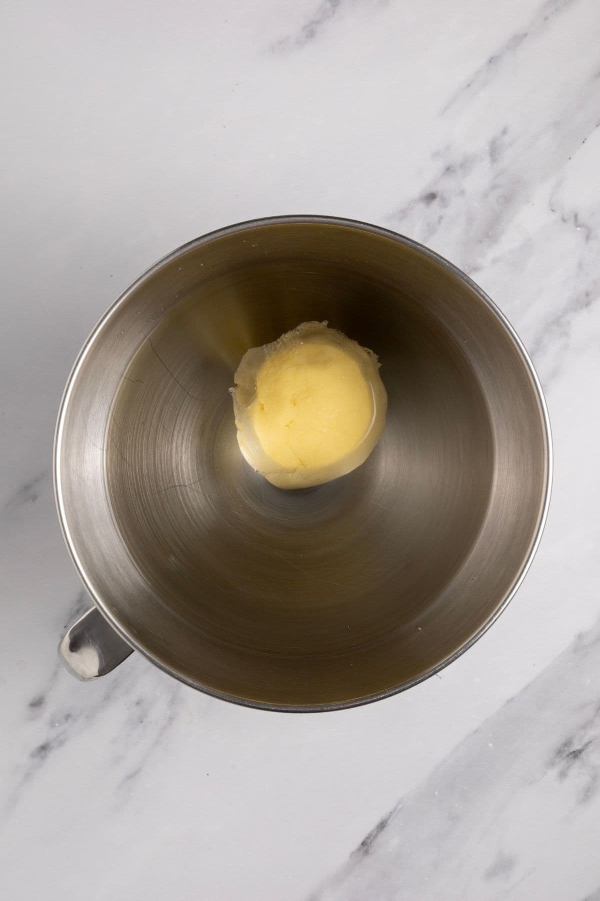 A ball of fresh cultured butter floating in a stand mixer bowl full of clean water.