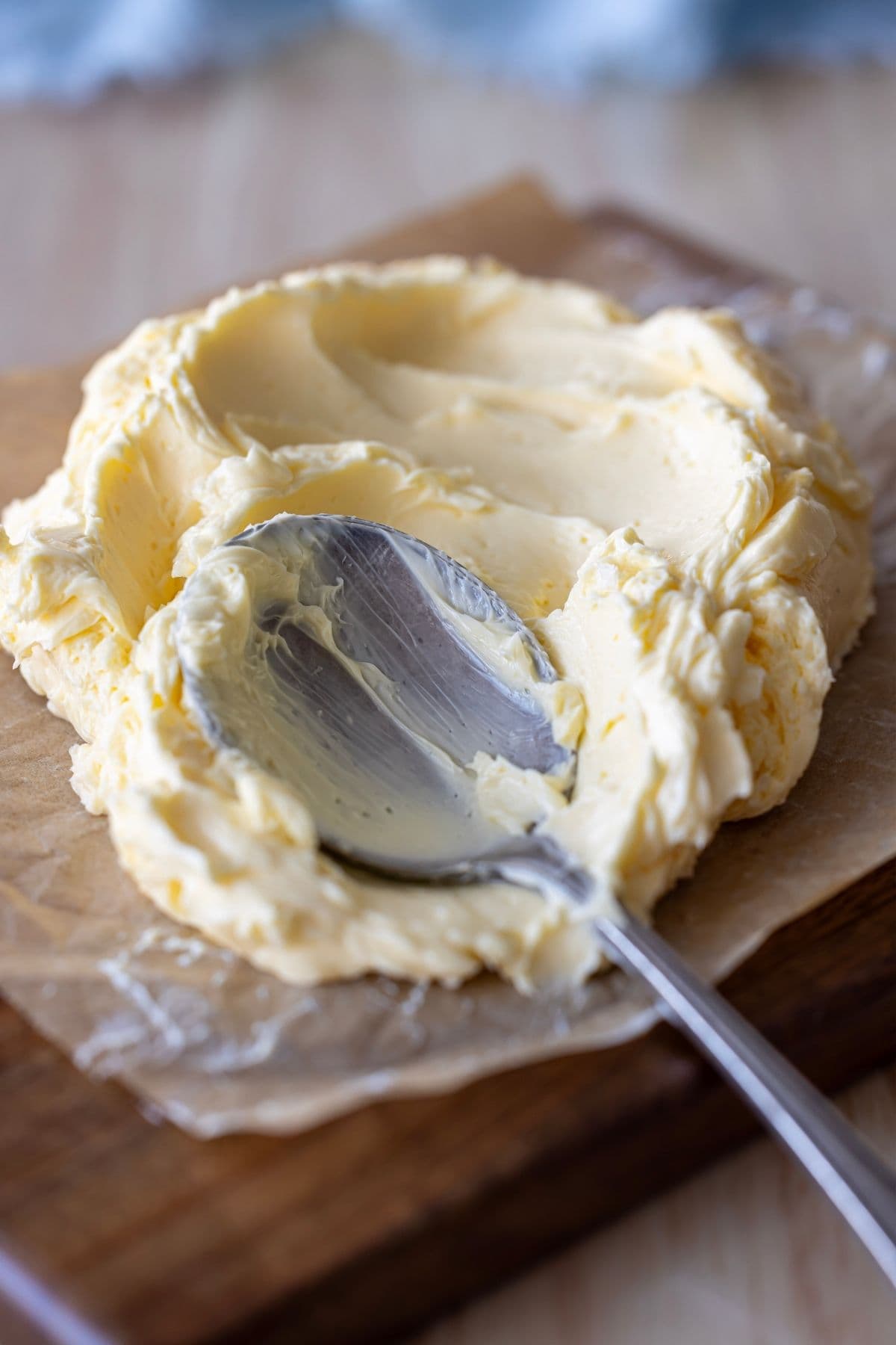 Cultured butter being smeared on a piece of parchment paper with a vintage spoon.