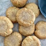 A stash of sourdough snickerdoodles rolled in cinnamon sugar. They've just been baked and arranged on a piece of parchment paper.