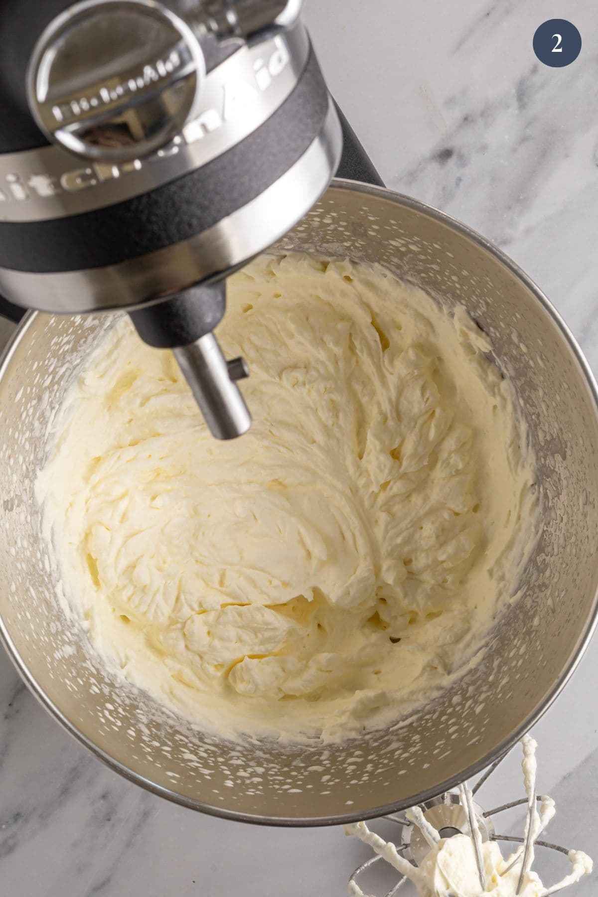 A stand mixer bowl showing the soft peaks of whipped cream. This demonstrates the first part of the process of making butter.