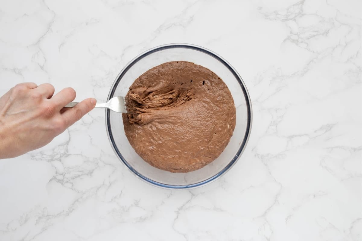 Fork stirring a bubbly chocolate sourdough preferment in a glass bowl before making the cake batter.