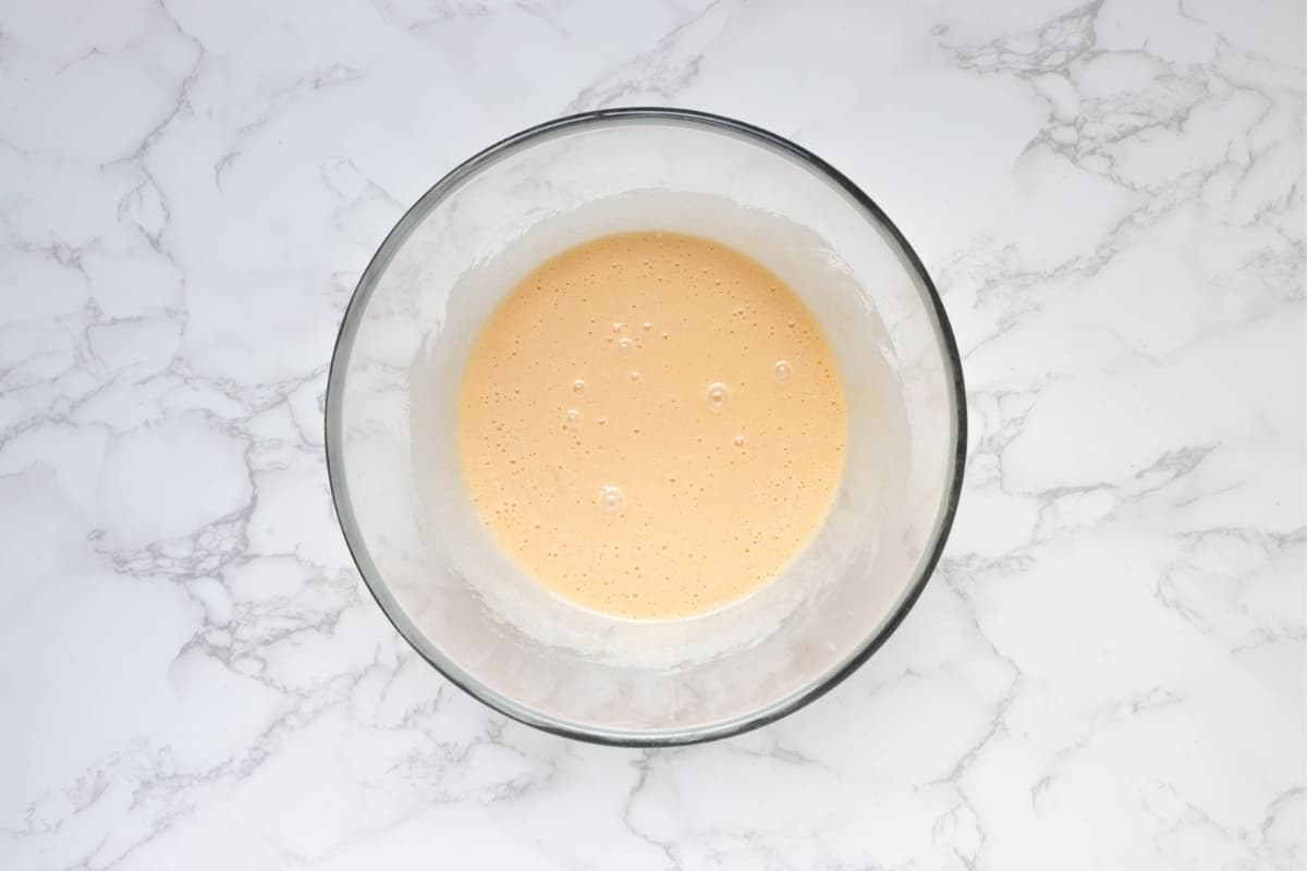 Wet cake batter ingredients whisked together in a glass bowl before adding cocoa and sourdough starter.