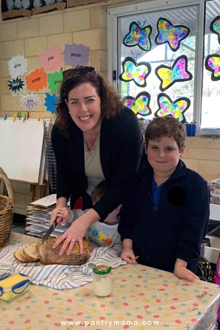 Sourdough for busy moms - easy sourdough recipe for time poor moms - this photo shows a mom and son slicing sourdough bread together with a jar of sourdough starter in front of them.