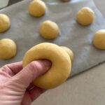 Using your thumb to create a hole in each bagel.