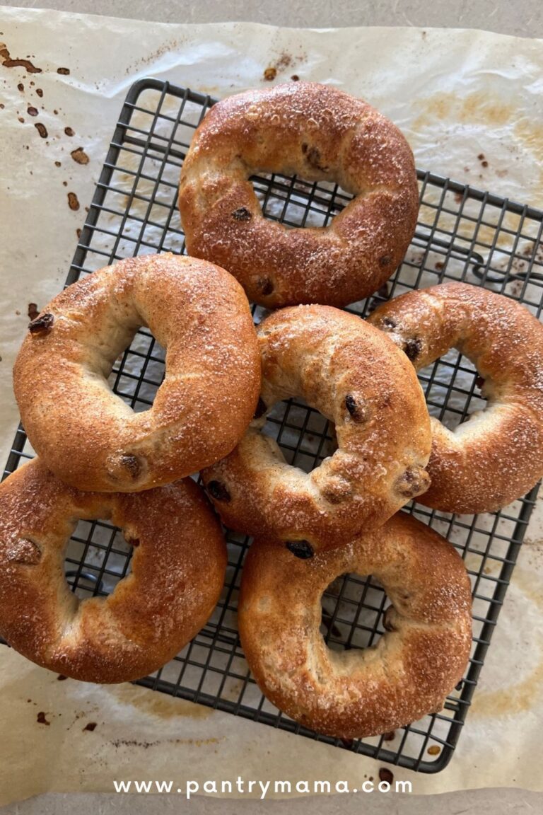 Baked cinnamon raisin sourdough bagels arranged on a black cooling rack.