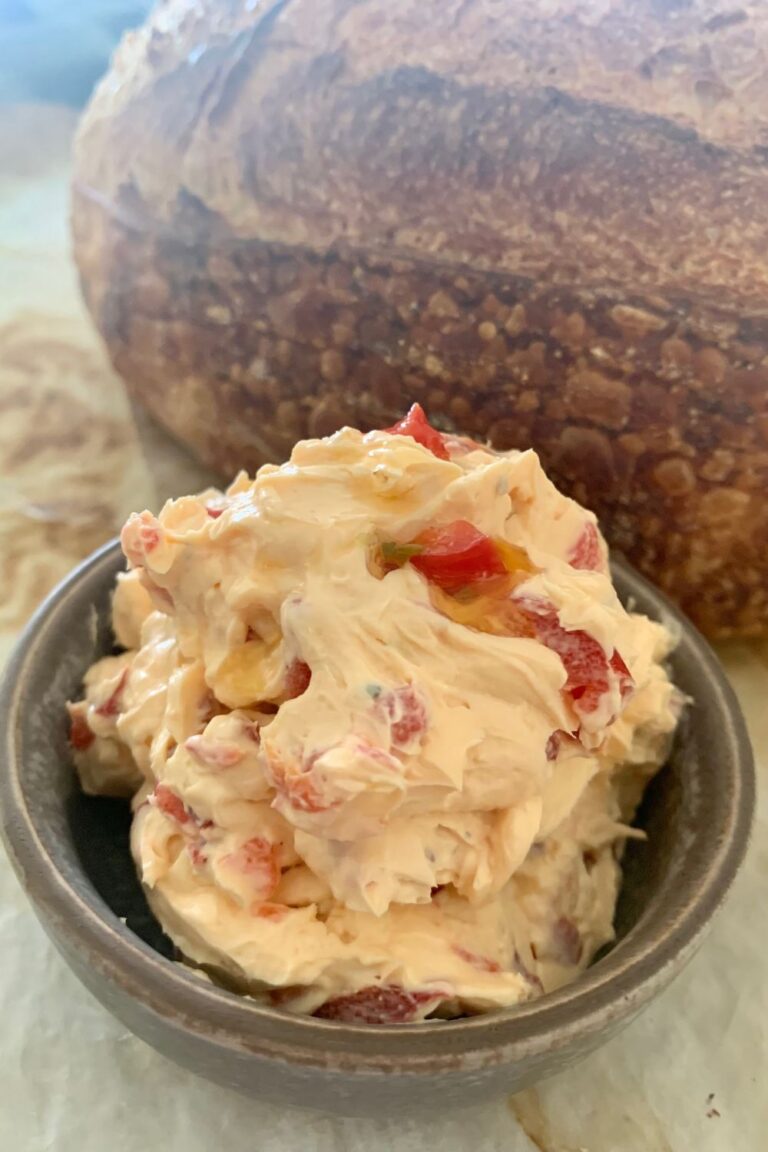 Roasted Red Pepper Cream Cheese Dip or Spread sitting in a bowl in front of a loaf of sourdough bread.