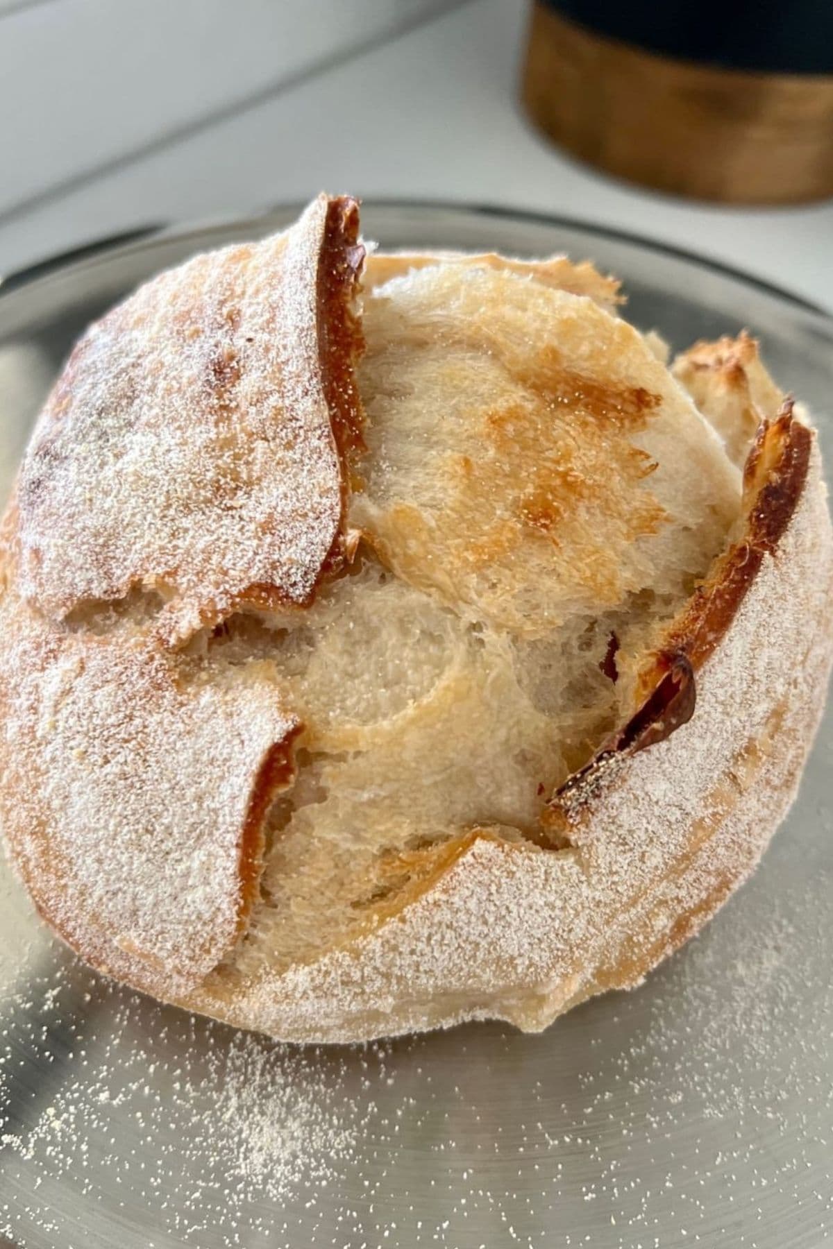 A small loaf of sourdough that looks dense and heavy. It has not been bulk fermented adequately, so the scoring is very exaggerated and has split.